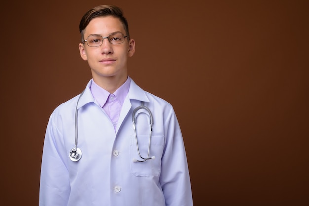 Foto de estúdio de um jovem médico bonito contra um fundo marrom