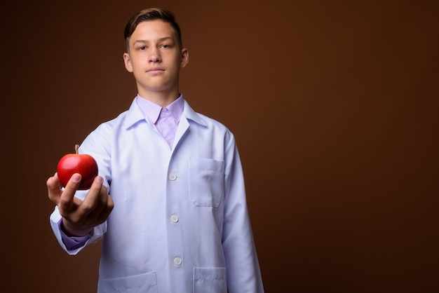 Foto de estúdio de um jovem médico bonito contra um fundo marrom