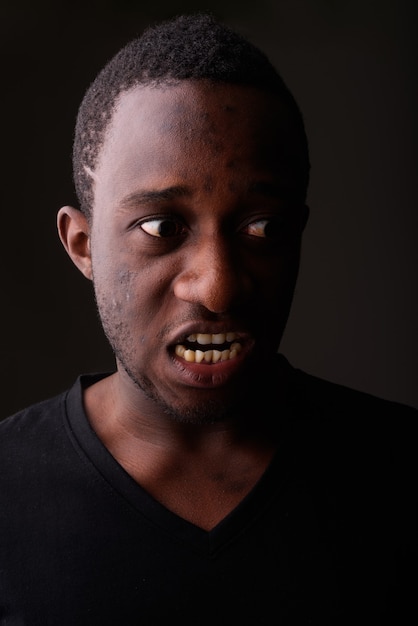 Foto de estúdio de um jovem negro africano furioso gritando no escuro r