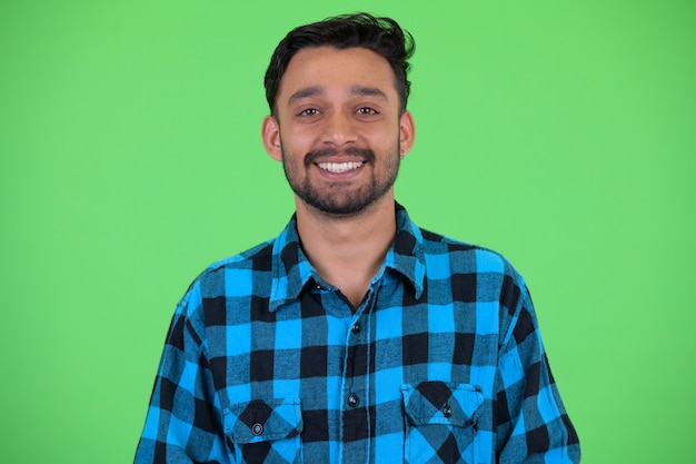 Foto de estúdio de um jovem persa barbudo e bonito homem hippie contra chroma key com fundo verde