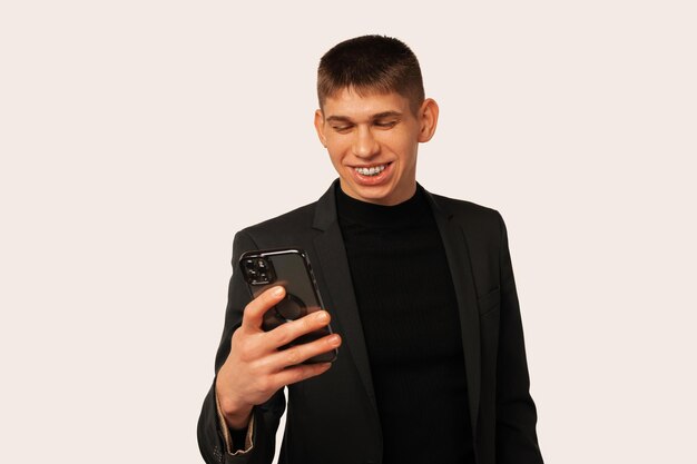 Foto de estúdio de um jovem sorridente está olhando para o telefone que está segurando