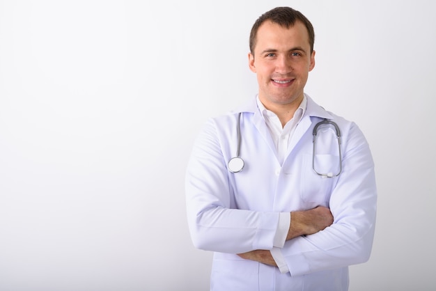 Foto de estúdio de um médico jovem feliz e musculoso sorrindo com os braços