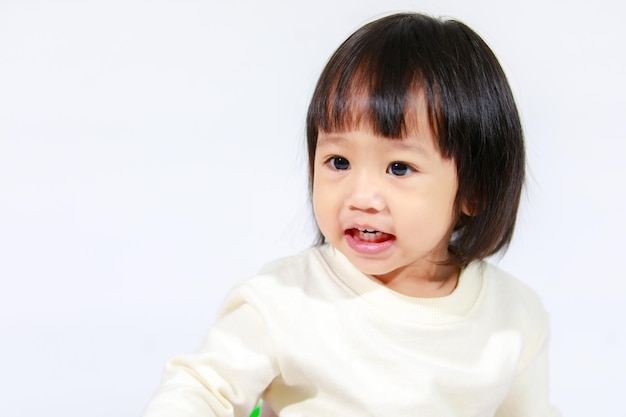 Foto de estúdio de um modelo de filha de bebê asiático de cabelo preto curto e bonito em saia xadrez casual sentada e sorrindo em fundo branco