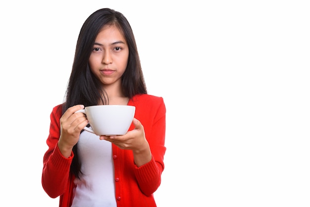 Foto de estúdio de uma jovem adolescente asiática segurando uma xícara de café