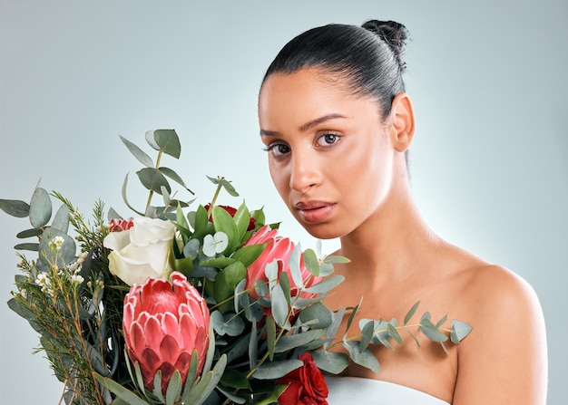 Foto de estúdio de uma jovem atraente segurando uma flor de protea contra um fundo cinza