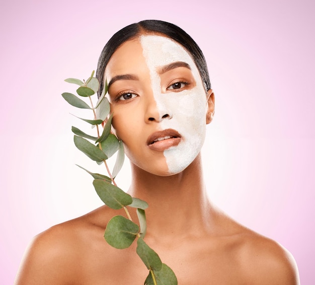 Foto de estúdio de uma jovem atraente segurando uma planta e tendo um tratamento facial contra um fundo rosa