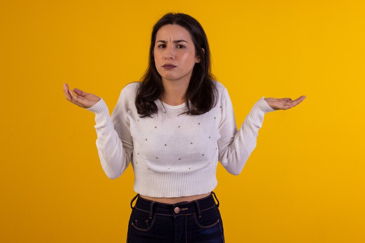 Foto foto de estúdio de uma jovem de camisa branca em fundo amarelo com várias expressões faciais