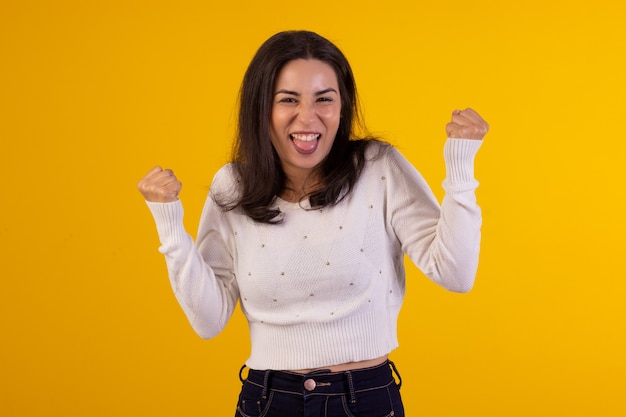 Foto de estúdio de uma jovem de camisa branca em fundo amarelo com várias expressões faciais