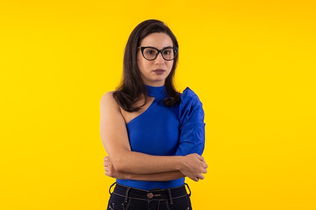 Foto de estúdio de uma jovem de óculos com blusa azul em fundo amarelo com várias expressões faciais