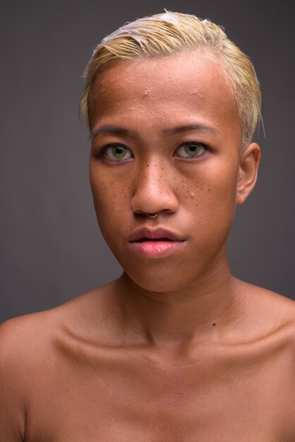 Foto de estúdio de uma jovem e bela mulher rebelde com cabelo curto contra o cinza