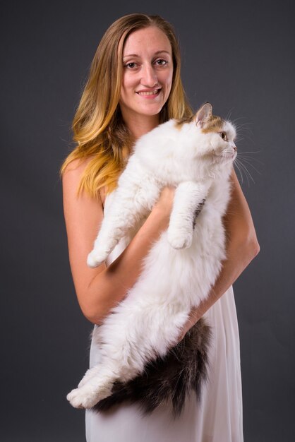 Foto de estúdio de uma jovem mulher bonita com cabelo loiro liso contra o cinza