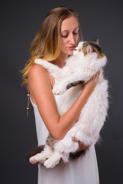 Foto de estúdio de uma jovem mulher bonita com cabelo loiro liso contra o cinza