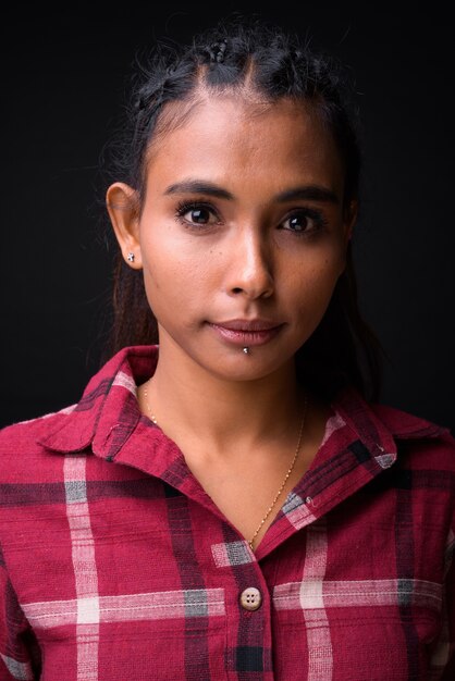 Foto foto de estúdio de uma jovem mulher bonita hippie asiática com cabelo trançado contra um fundo preto