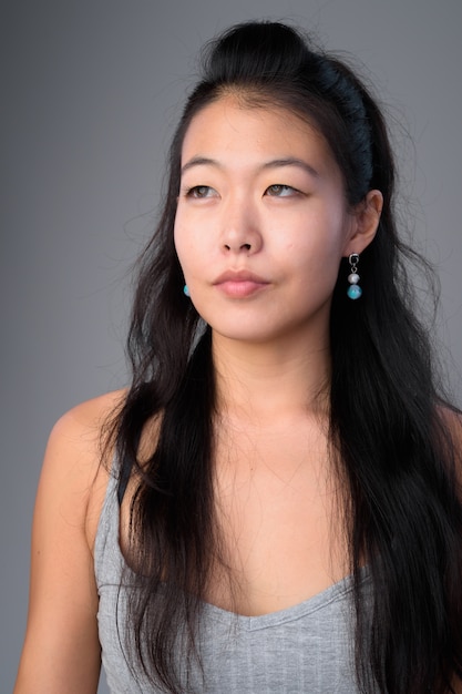 Foto de estúdio de uma linda mulher asiática contra um fundo cinza