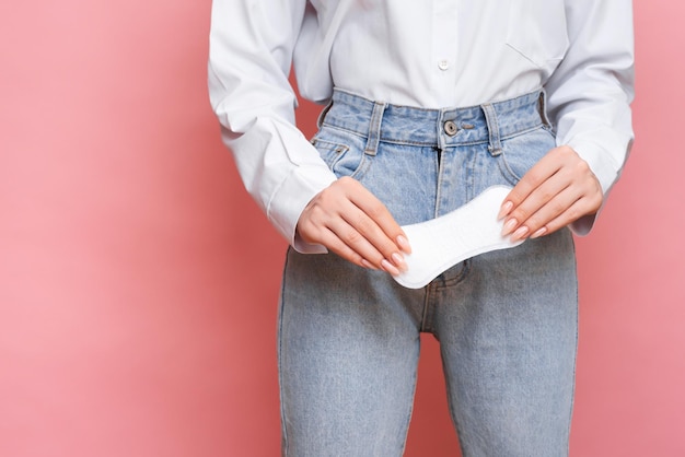 Foto de estúdio de uma menina segurando um pantyliner na mão, para a menstruação. o conceito de higiene feminina.