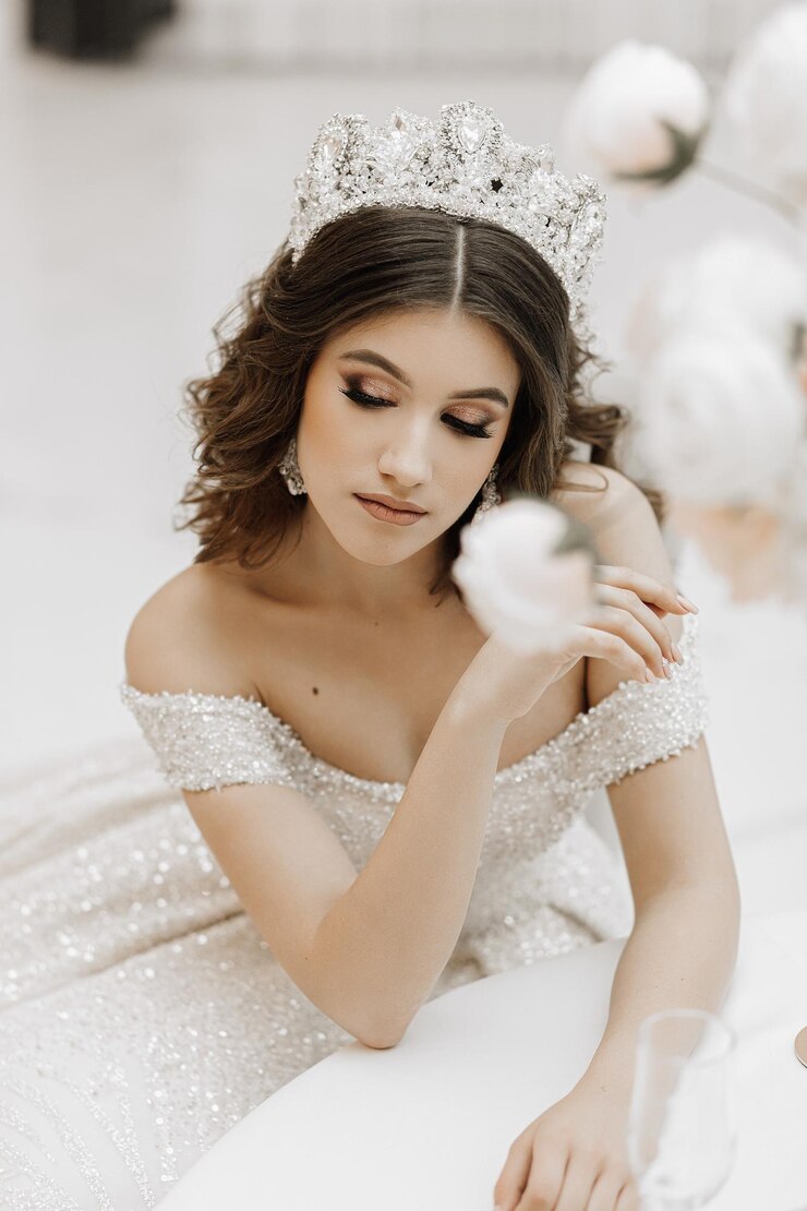 Foto foto de estúdio de uma princesa em um vestido de noiva com um penteado de luxo e maquiagem a noiva está sentada na mesa