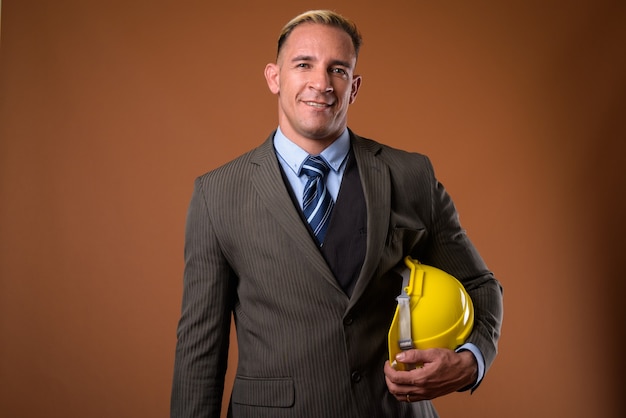 Foto de estúdio do empresário da construção segurando um capacete de segurança