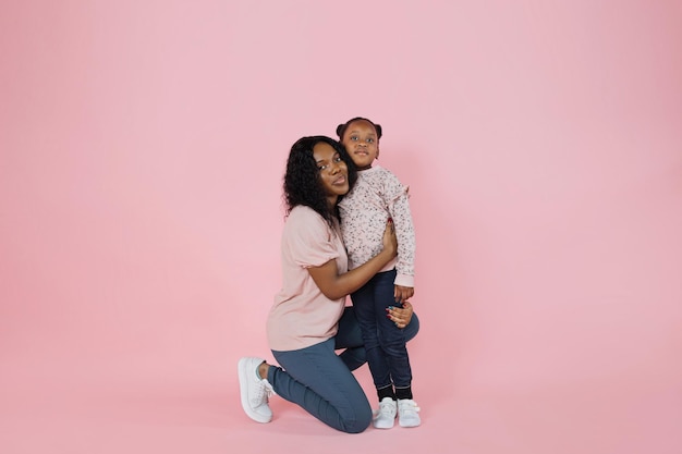 Foto de estúdio interior de uma jovem e agradável mãe africana e sua linda e adorável filhinha