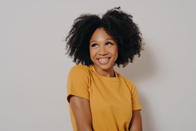 Foto de estúdio perto do retrato de uma garota afro-americana vestida casualmente com expressão de rosto engraçado