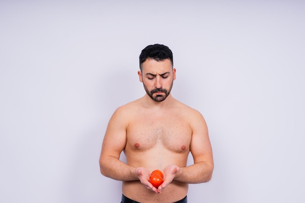 Foto de estúdio totalmente isolada de um jovem nu com cueca e tomate