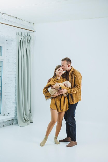 Foto de família caseira em um fundo branco de pais felizes com um bebê recém-nascido dormindo em seus braços Uma mãe e um pai felizes seguram seu filho de 4 meses em seus brazos