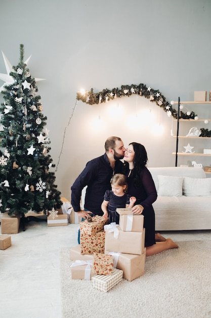 Foto de família com uma criança sentada no sofá ao lado da árvore de Natal e relaxando