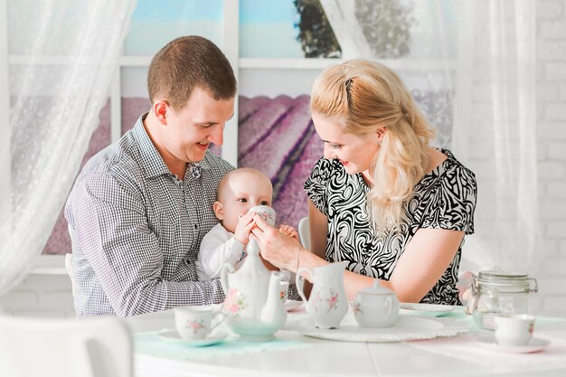 Foto de família feliz sentada com seu filho pequeno à mesa