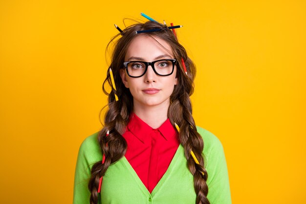 Foto de garota séria com corte de cabelo bagunçado com roupa estilo geek isolada em fundo de cor amarela