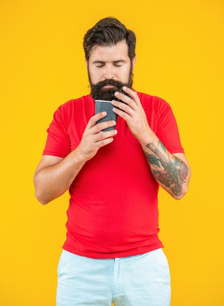 Foto de homem barista cheirando café homem barista segurando café isolado em amarelo