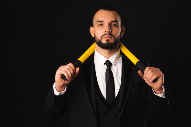 Foto de homem bonito em terno de formato segurando nunchaku e olhando sério para a câmera