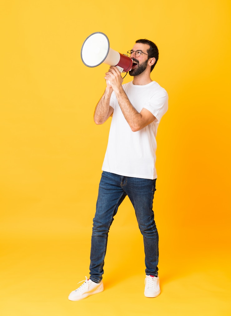 Foto foto de homem com barba sobre amarelo isolado gritando através de um megafone