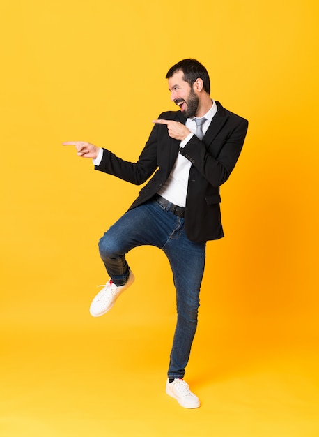 Foto de homem de negócios, apontando para a lateral sobre amarelo isolado