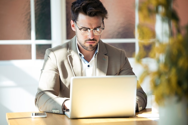 Foto de homem de negócios jovem bonito trabalhando com o laptop no escritório.