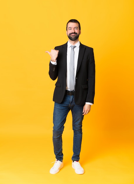 Foto de homem de negócios sobre amarelo isolado apontando para o lado para apresentar um produto