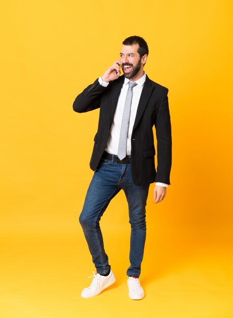 Foto de homem de negócios sobre amarelo isolado, mantendo uma conversa com o telefone móvel