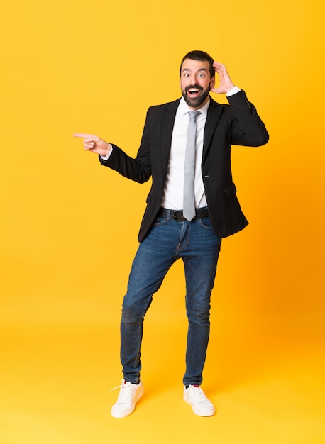 Foto de homem de negócios sobre amarelo surpreso e apontando o dedo para o lado