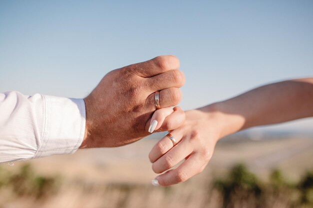 Foto de homem e mulher com aliança de casamento Jovem casal de mãos dadas cerimônia dia do casamento Mãos de casal recém-casado com alianças de casamento