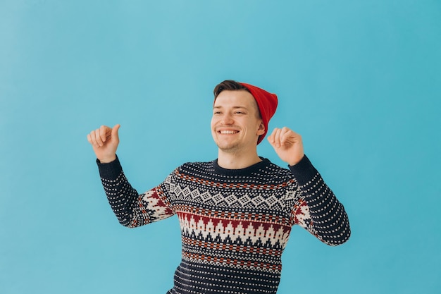 Foto foto de homem encantador vestindo suéter de natal e chapéu vermelho isolado em fundo azul