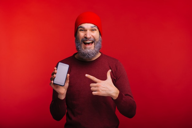 Foto de homem espantado com barba branca, apontando para o seu smartphone