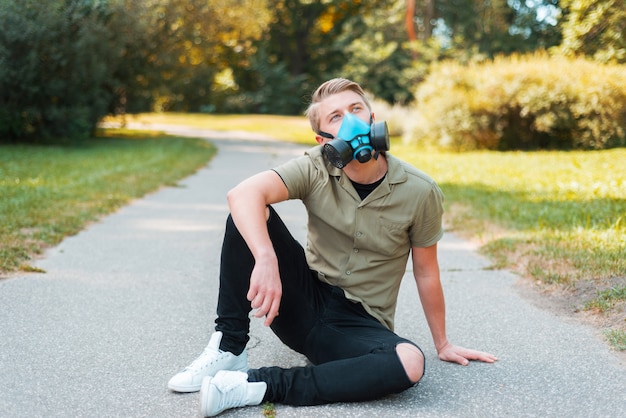 Foto de homem usando respirador facial ao ar livre no parque e olhando para longe.