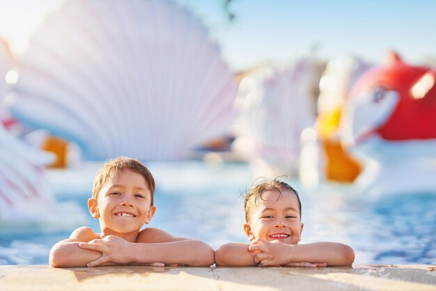 Foto de irmãos brincando na piscina do parque aquático ao ar livre