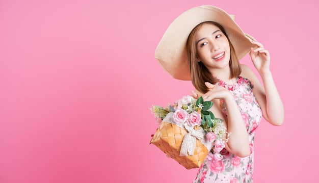 Foto de jovem asiática usando vestido de flores em fundo rosa