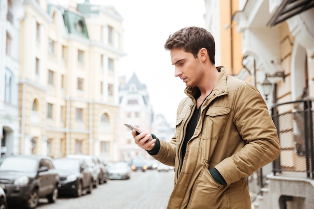 Foto de jovem caminhando na rua e conversando ao lado de seu telefone ao ar livre. olhe para o telefone.