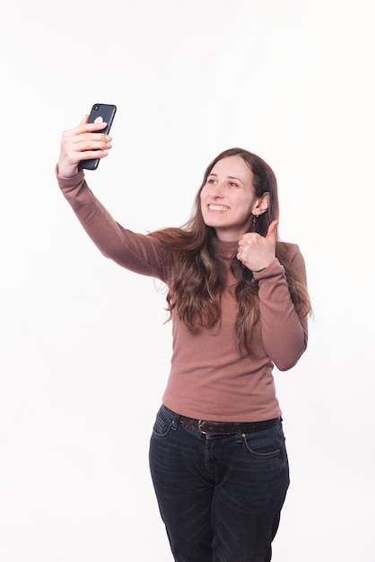 Foto de jovem casual tomando selfie e mostrando o polegar