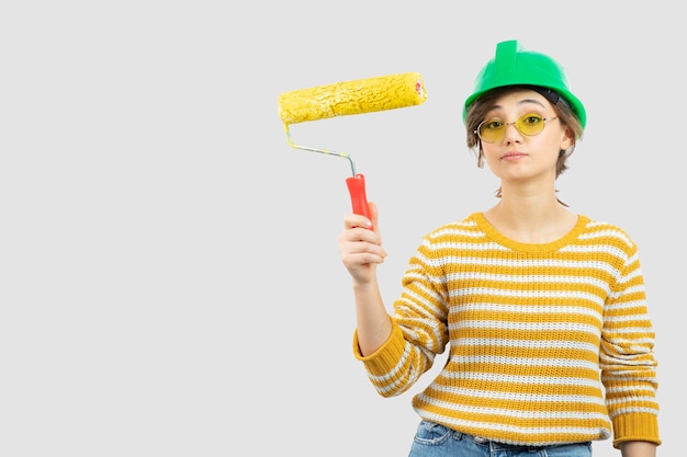 Foto de jovem com capacete de segurança verde, segurando um rolo de pintura na mão. Foto de alta qualidade