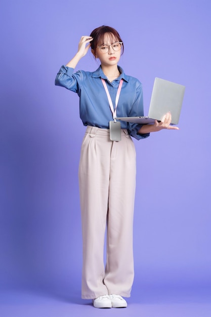 Foto de jovem empresária asiática segurando laptop em segundo plano
