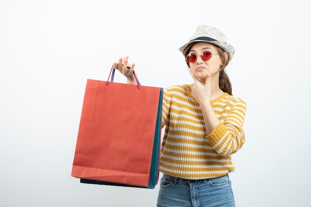 Foto de jovem morena em óculos de sol segurando sacolas de compras. Foto de alta qualidade