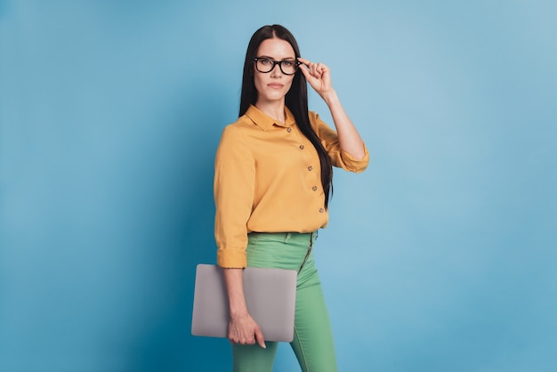 Foto de jovem mulher de negócios com laptop moderno em trajes formais em fundo azul