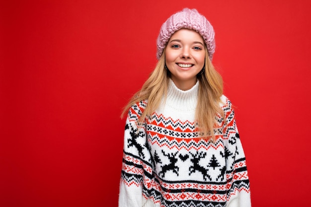 Foto de jovem positiva, feliz, linda loira, com emoções sinceras, usando um chapéu de malha rosa