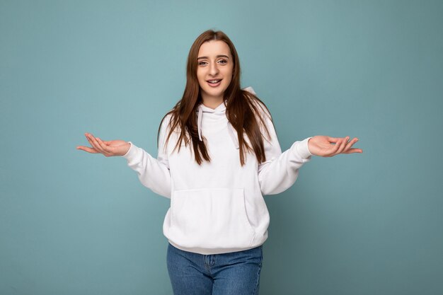 Foto de jovem positiva feliz linda morena com emoções sinceras usando um capuz branco